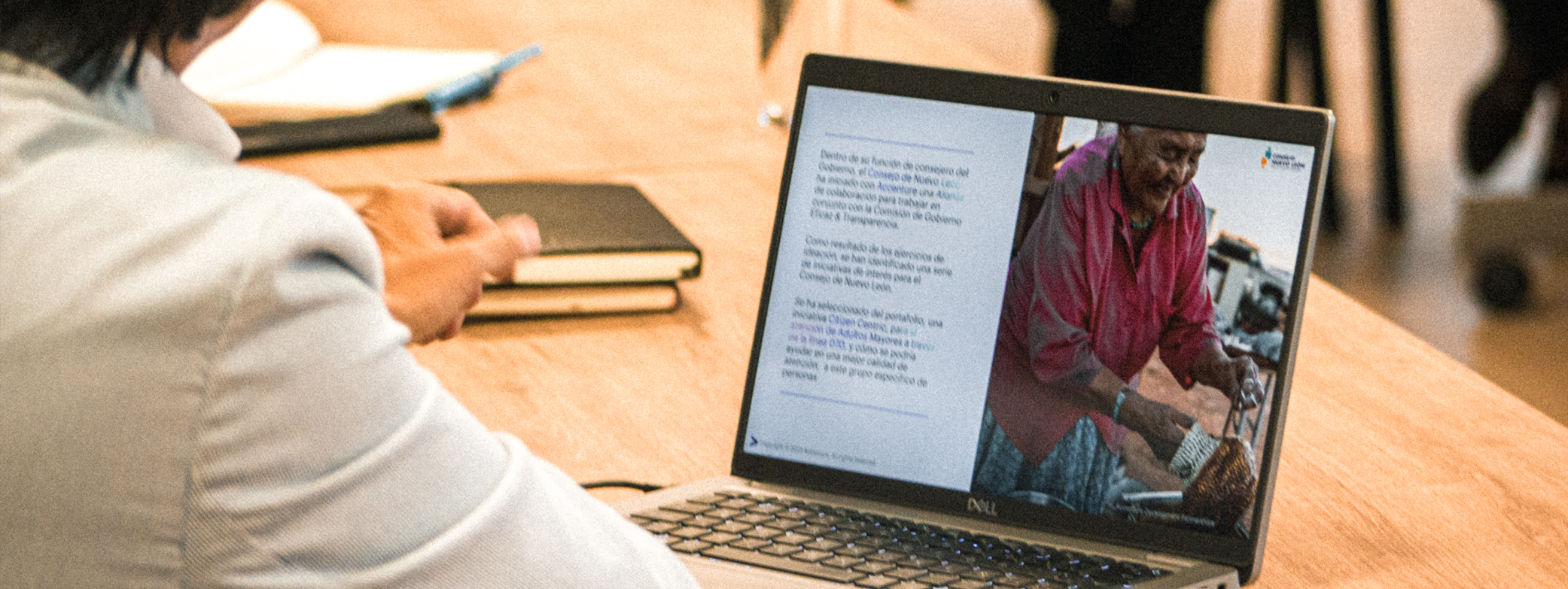 Un hombre trabaja en una computadora con una presentación que ilustra a una mujer trabajando en una artesanía.