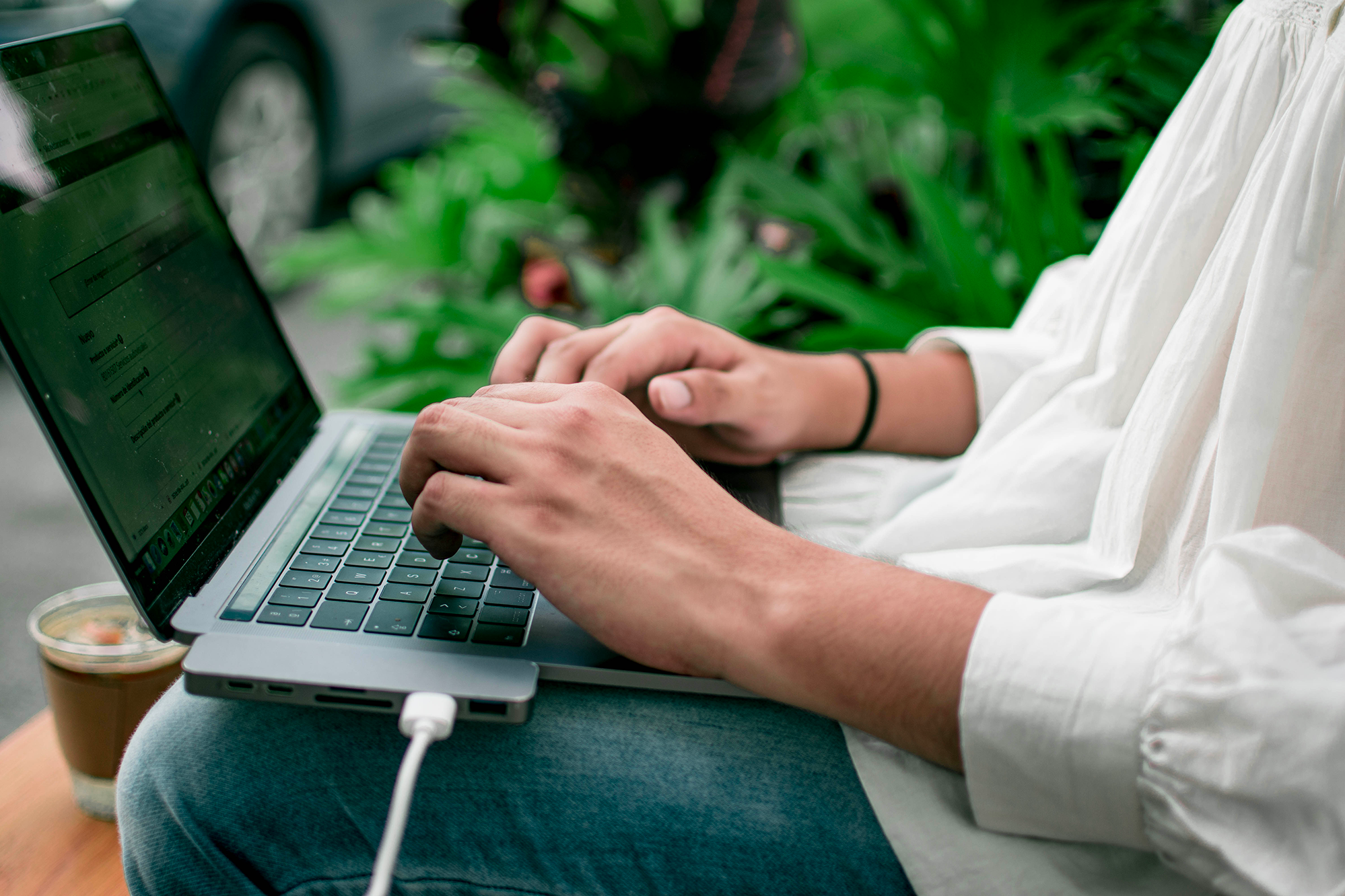 Un hombre escribiendo en una laptop. La laptop está conectada con un table.